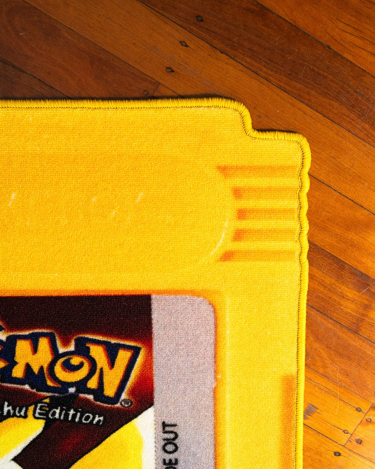 Pokemon Yellow cartridge cut-out rug shown for scale in a room